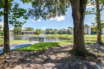 A park with a pond and trees with a building in the background